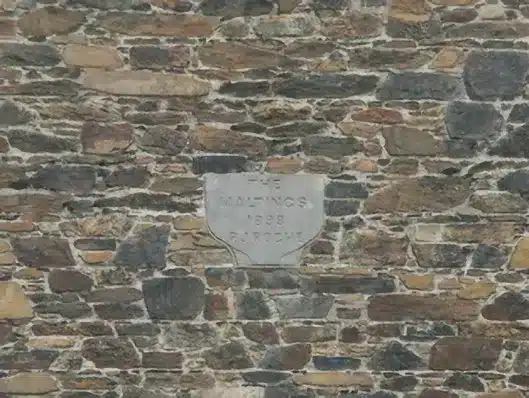 Plaque on old stone wall in Enniscorthy, with weathered text reading The Maltings, 1898, P J Roche.