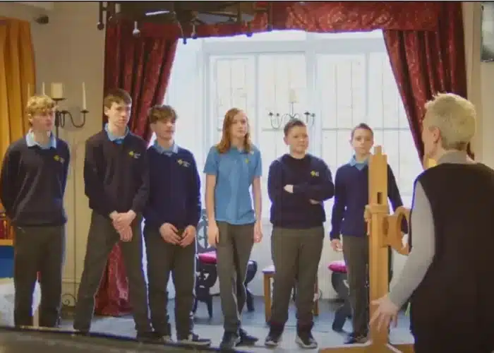 Group of students in school uniforms listening to a guide during an educational visit inside Enniscorthy Castle.