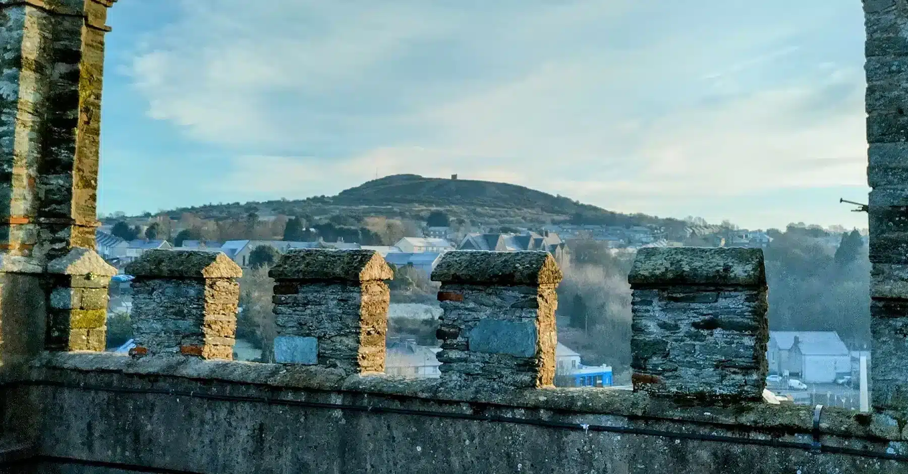 View from a stone castle battlement of Enniscorthy Castle, overlooking Vinegar Hill in the distance.