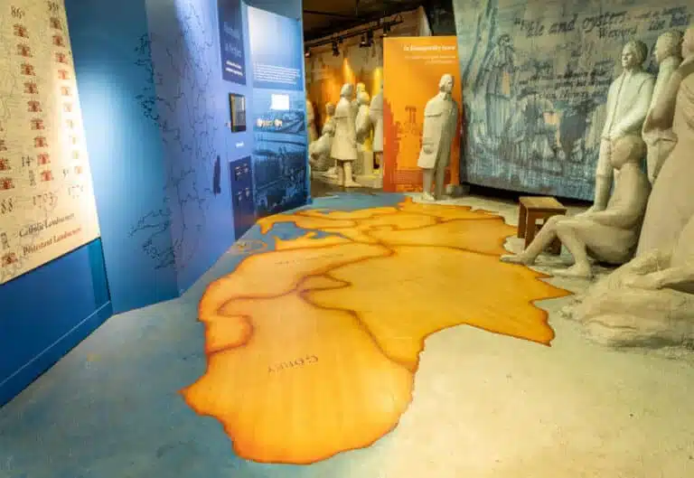 Exhibition space at the National 1798 Rebellion Centre, Enniscorthy, featuring a large floor map, informational panel and sculpted figures representing people from the era.