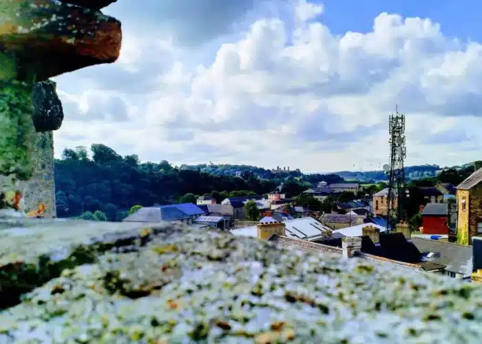 View from Enniscorthy Castle looking over the town’s rooftops toward distant hills under a bright, cloudy sky.