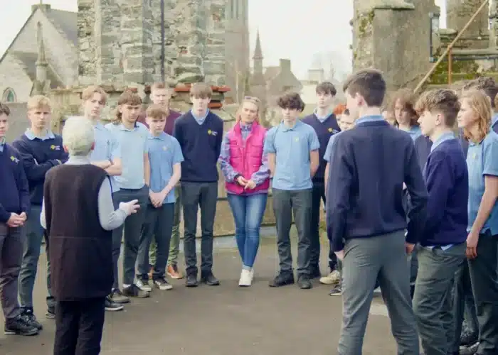 Group of students standing in a circle around a guide during an outdoor tour at Enniscorthy Castle.